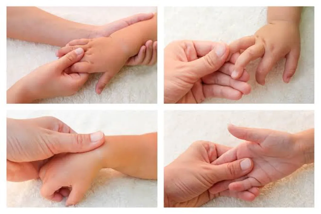 Adult hands gently massaging a child's hands.